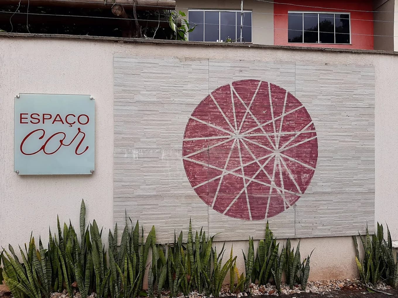Fachada do Espaço Cor no Setor Sul, em Goiânia, com o mandala da marca pintado na parede de pedra e a placa Espaço Cor