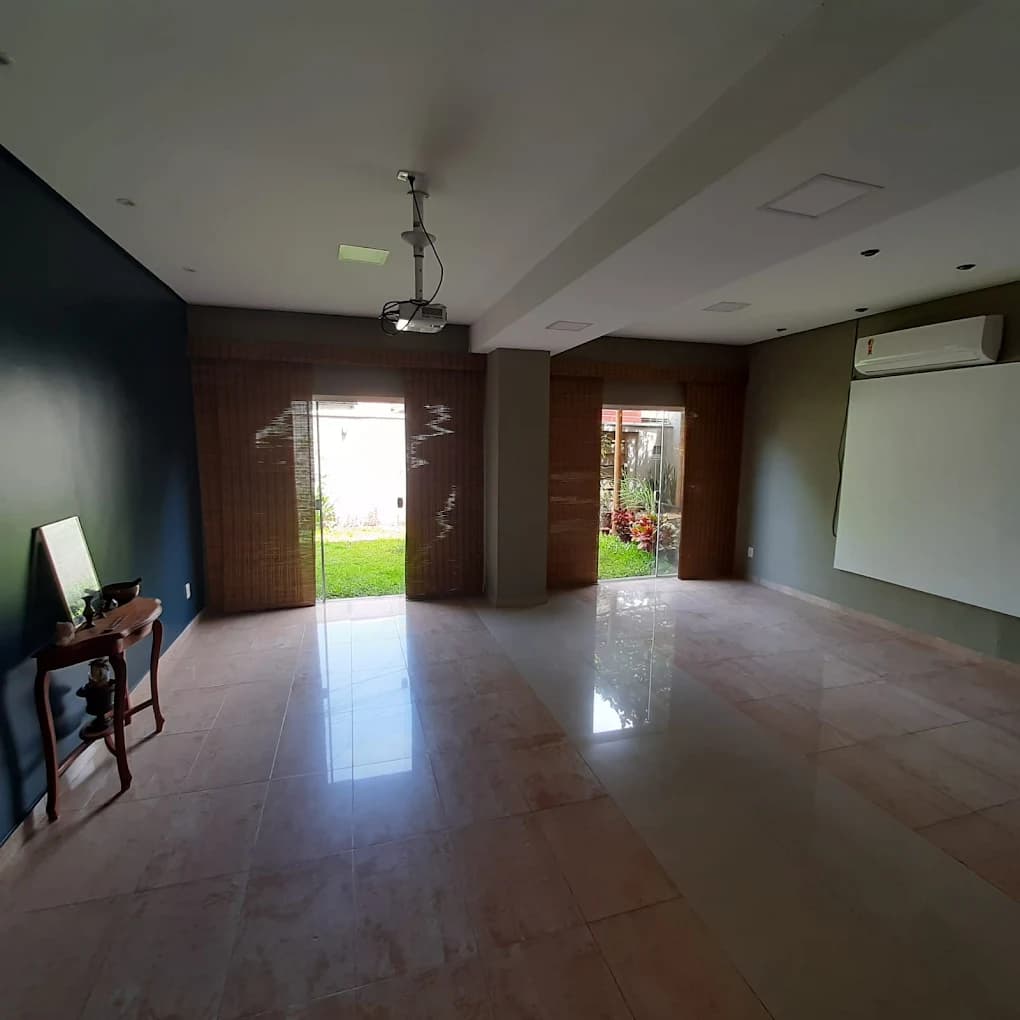 Salão de eventos do Espaço Cor: 50 m² com piso espelhado, projetor no teto e portas de vidro abrindo para o jardim